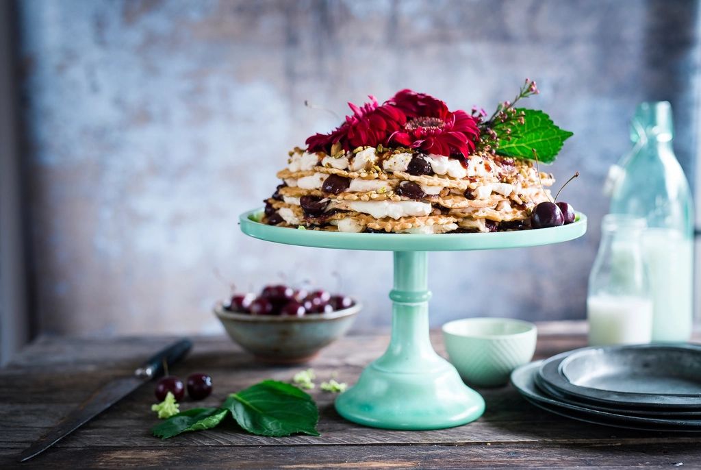 Bolo alto com flores e frutas vermelhas sobre boleira