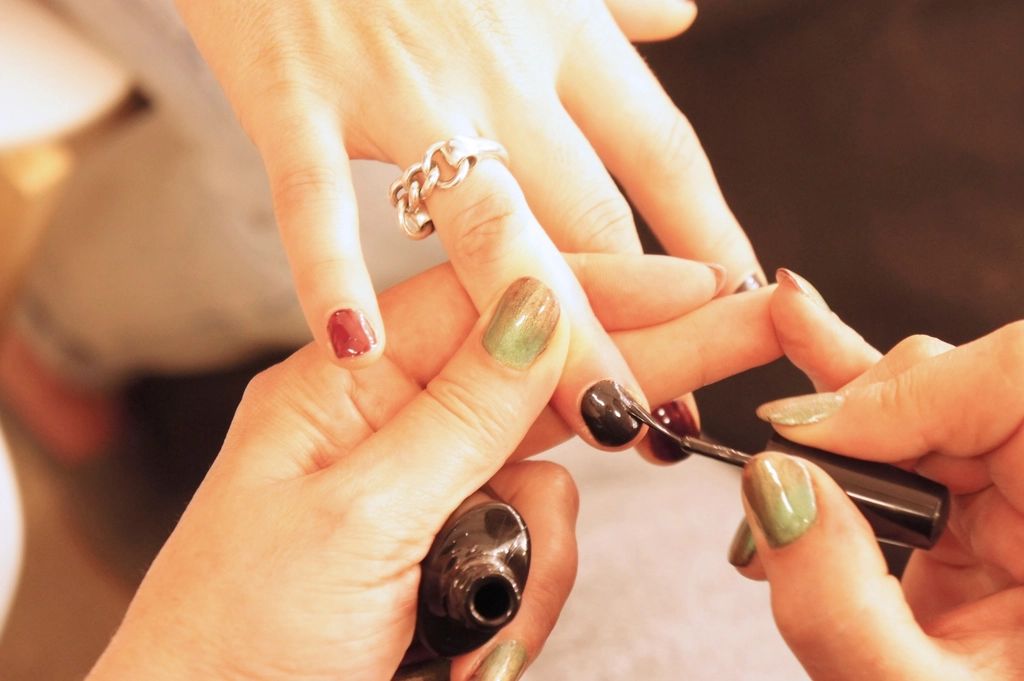 Unhas sendo pintadas com esmalte escuro