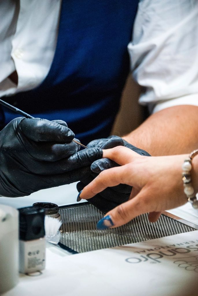 Profissional de luvas fazendo a unha de uma cliente